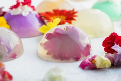 A clear dome shaped cake with a pink flower in the middle.