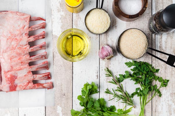 a rack of lamb next to measured ingredients like parsley, garlic, parmesan cheese