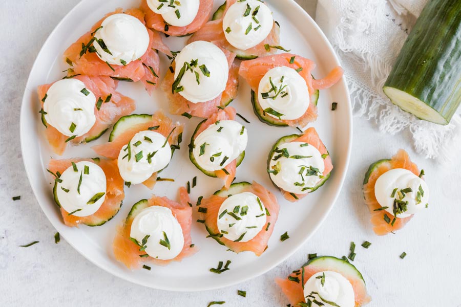 a platter with a bunch of cucumber and salmon finger foods on it