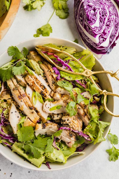 a salad with leafy greens tossed around and a purple cabbage wedge above