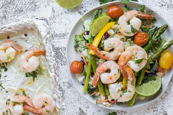 cooked shrimp topped on a salad with a tray of shrimp