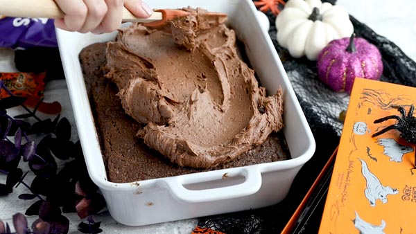 spreading chocolate buttercream frosting on a cake